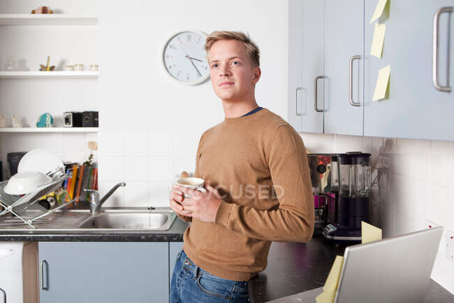 Jeune homme dans la cuisine avec tasse à café — Photo de stock