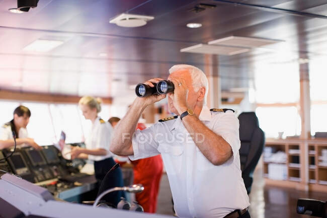 Capitán en la nave mirando a través de un telescopio - foto de stock