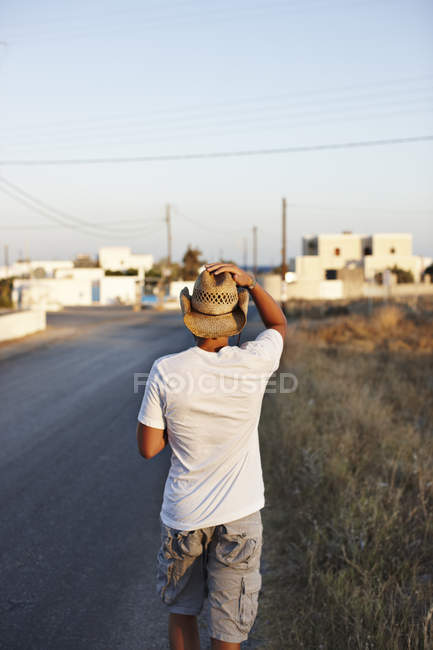 Вид сзади на человека, идущего по сельской дороге — стоковое фото