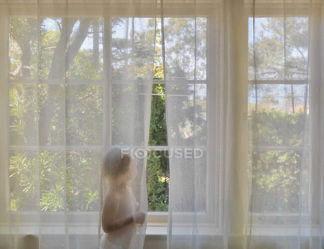 Garçon debout derrière le rideau transparent — Photo de stock