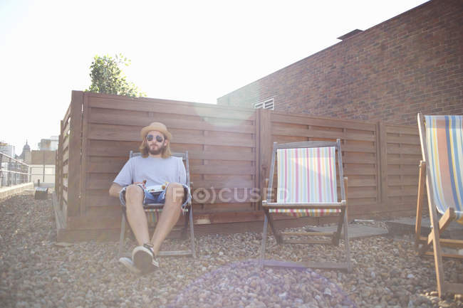 Jovem sozinho em cadeira de praia na festa no telhado — Fotografia de Stock