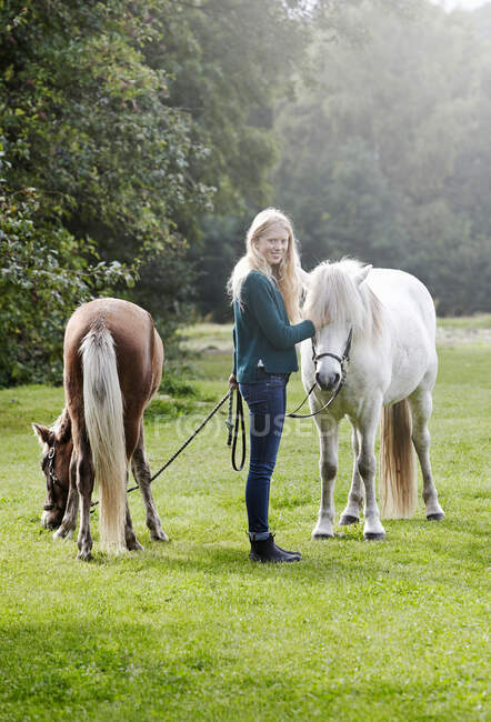 Mädchen zu Fuß Pferde in Feld — Stockfoto
