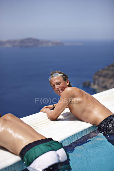 Adolescentes relajándose en la piscina infinita - foto de stock