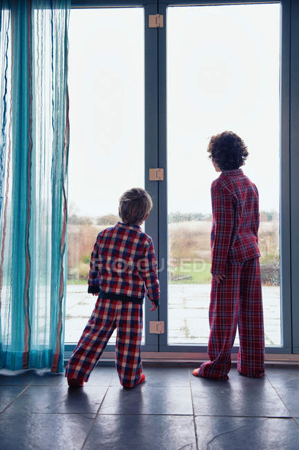 Jungen im Schlafanzug schauen aus dem Fenster — Stockfoto