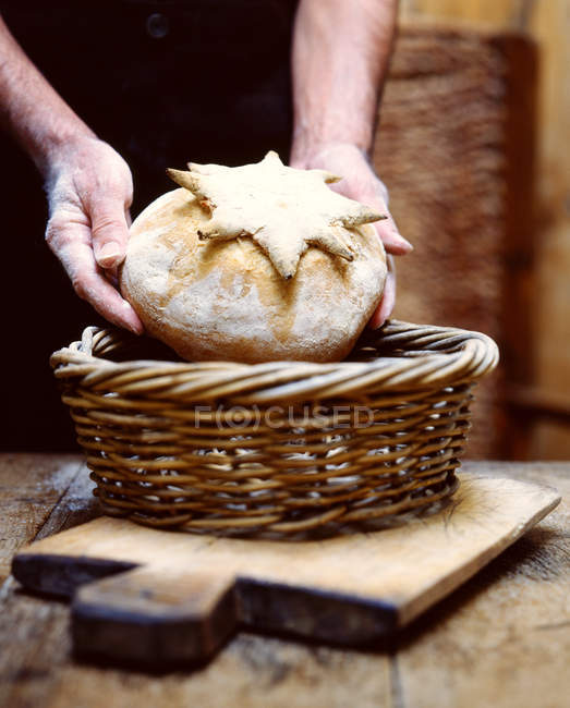 Imagen recortada de panadero poniendo pan casero en la cesta - foto de stock