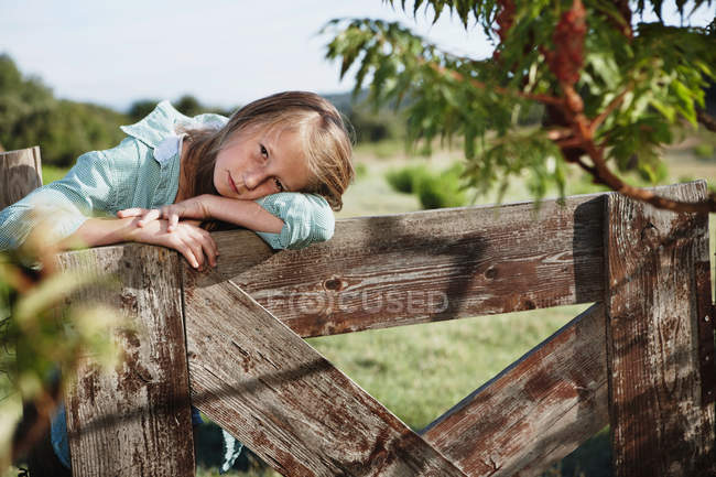 Petite fille appuyé sur la clôture à l'extérieur — Photo de stock