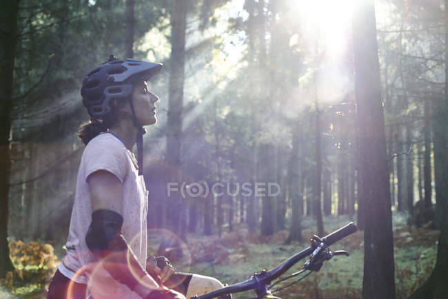 Mountainbikerin steht mit geschlossenen Augen im Sonnenstrahl, Wald von Dekan, Bristol, UK — Stockfoto