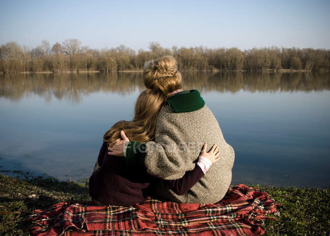 Grandmother and granddaughter by river — Stock Photo