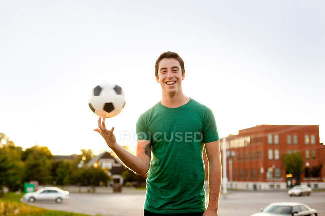 Homme tournant ballon de football sur le doigt, mise au point sélective — Photo de stock