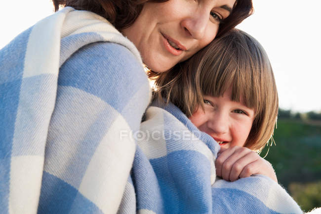 Madre e hija envueltas en manta - foto de stock