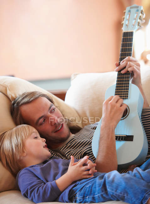 Отец и сын играют на укулеле — стоковое фото