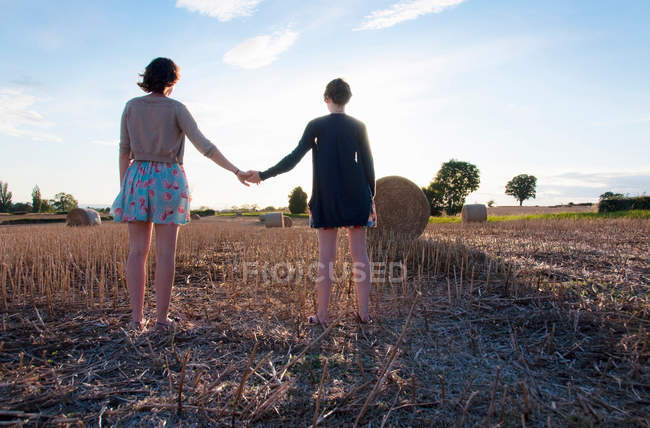 Rear view of girls holding hands in hayfield — Stock Photo