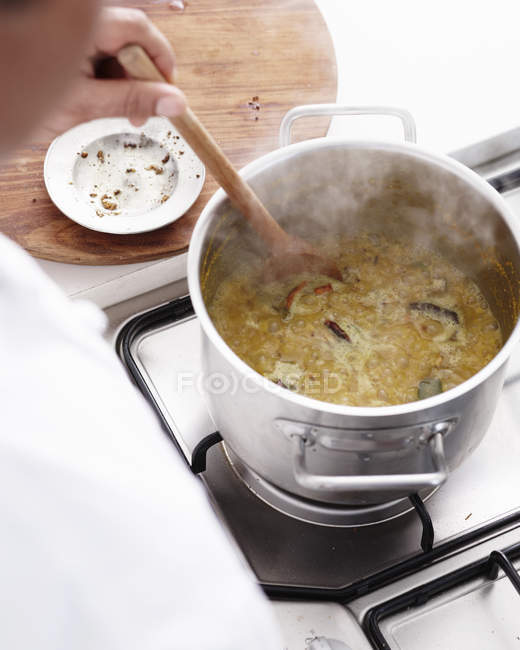 Persona mezclando curry caliente en olla - foto de stock