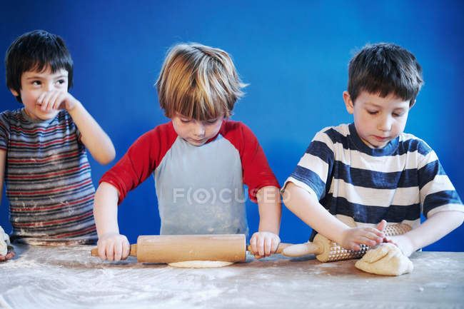Jungen rollen Teig mit Nadeln aus — Stockfoto