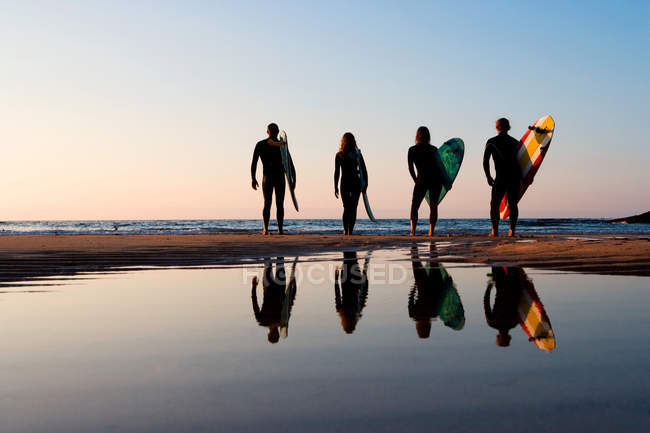 Cuatro personas de pie en la playa - foto de stock