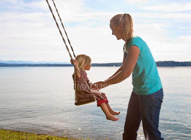 Madre spingendo figlia su swing — Foto stock