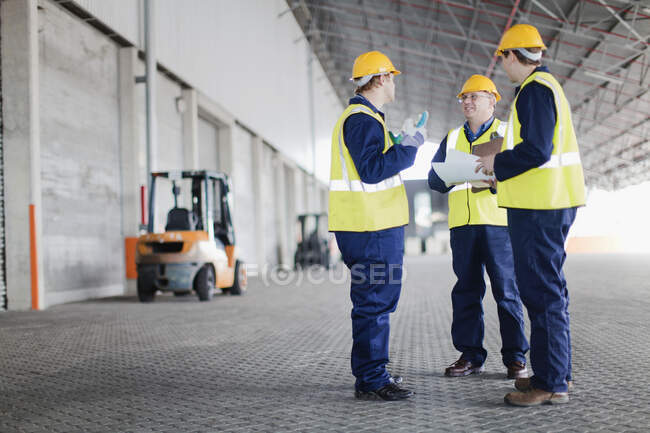 Travailleurs parlant dans un entrepôt — Photo de stock