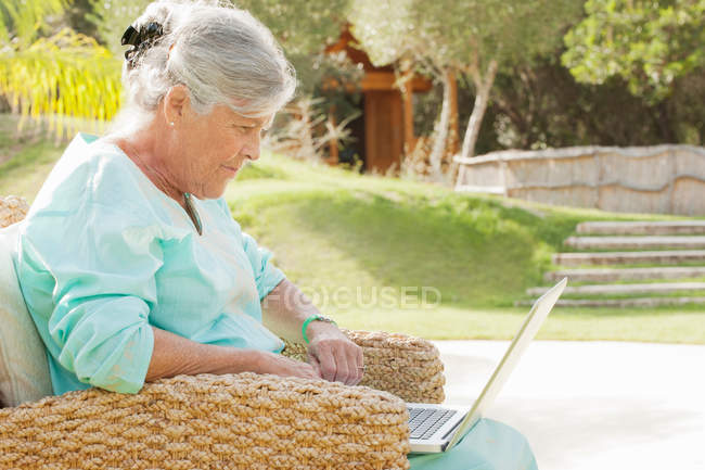 Donna anziana che utilizza il computer portatile all'aperto — Foto stock
