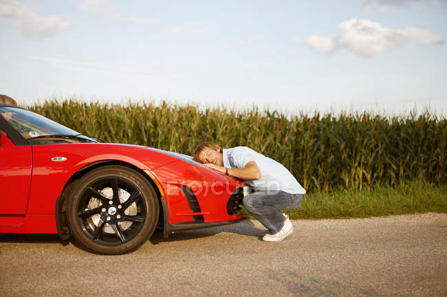Чоловік обіймає свій електричний спортивний автомобіль — стокове фото