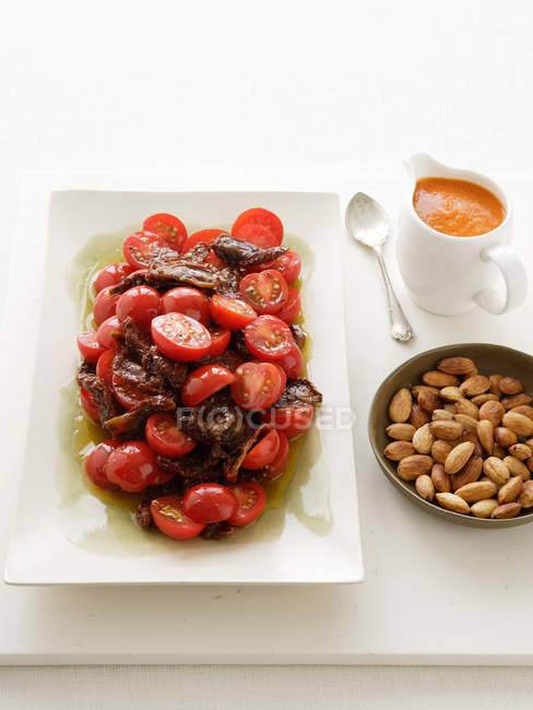 Ensalada de tomate en plato con almendras - foto de stock