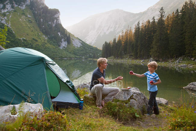 Padre e hijo comiendo en el camping - foto de stock