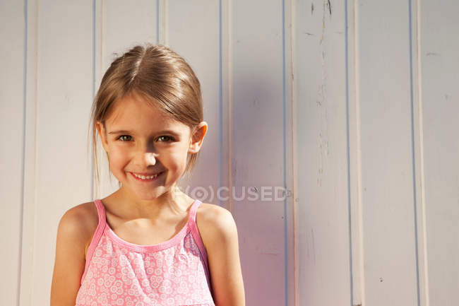Маленькая девочка перед деревянной стеной — стоковое фото