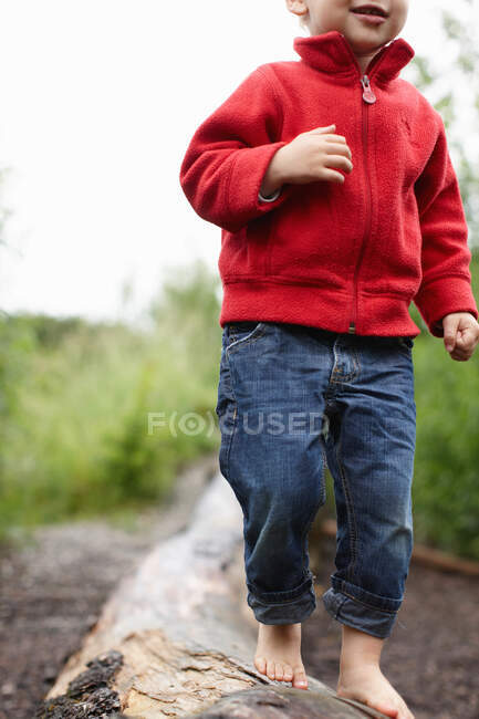 Menino criança andando descalço no log — Fotografia de Stock
