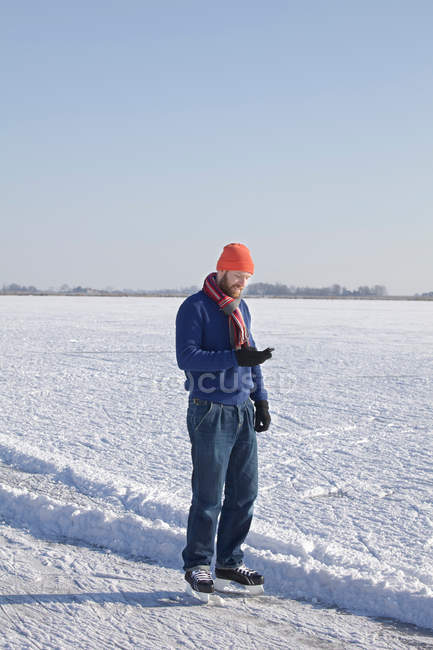 Man in ice skates using cell phone — Stock Photo
