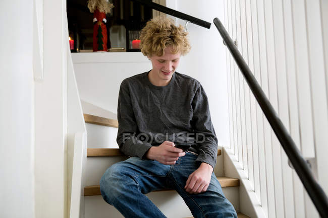 Adolescent garçon à l'aide de téléphone cellulaire sur escaliers — Photo de stock