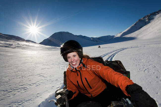 Mulher dirigindo snowmobile no campo nevado — Fotografia de Stock
