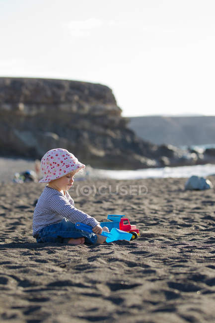 Criança brincando com pá na praia — Fotografia de Stock