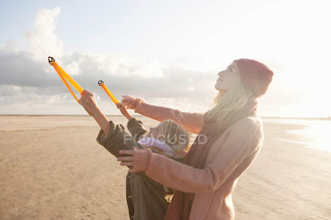 Mother and daughter flying kite on beach — Stock Photo