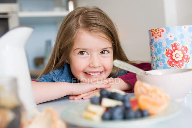 Chica sonriendo detrás de algunos alimentos saludables - foto de stock