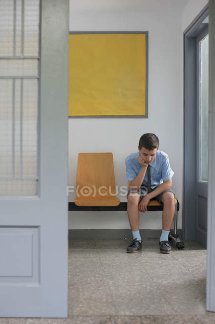 Мальчик, сидящий вне офиса — стоковое фото