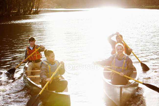 Friends rowing canoes on still lake — Stock Photo