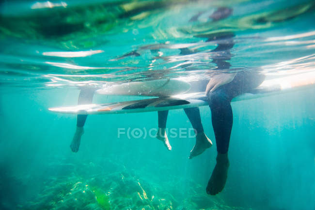 Couple's legs and surfboards underwater — Stock Photo