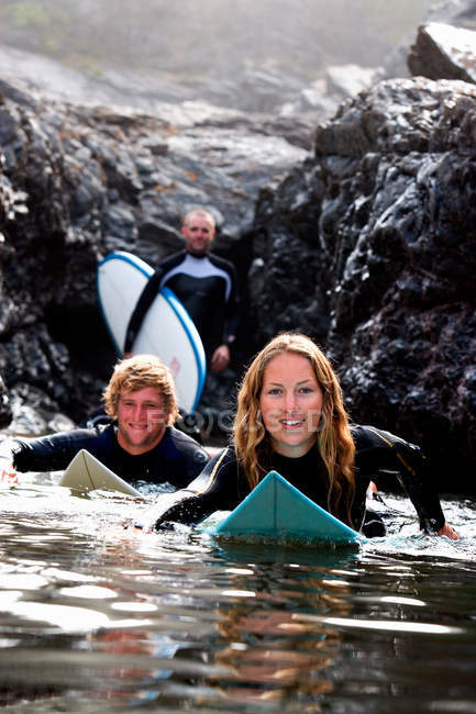 Trois personnes avec des planches de surf souriantes — Photo de stock