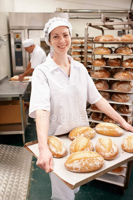 Chef carrying tray of bread in kitchen — Stock Photo