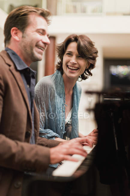 Пара, играющая вместе на пианино дома — стоковое фото