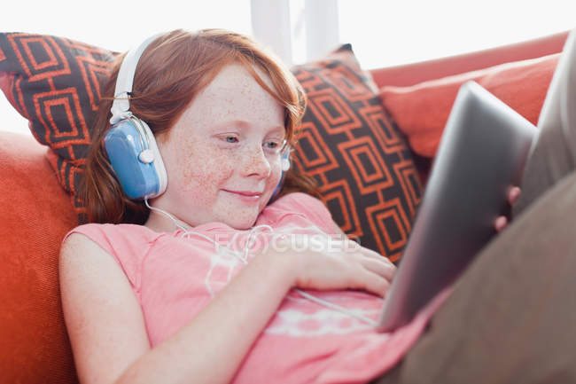 Menina em fones de ouvido usando computador tablet — Fotografia de Stock