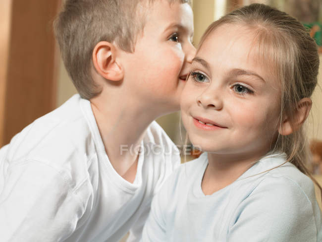 Boy whispering in girls ear — Stock Photo