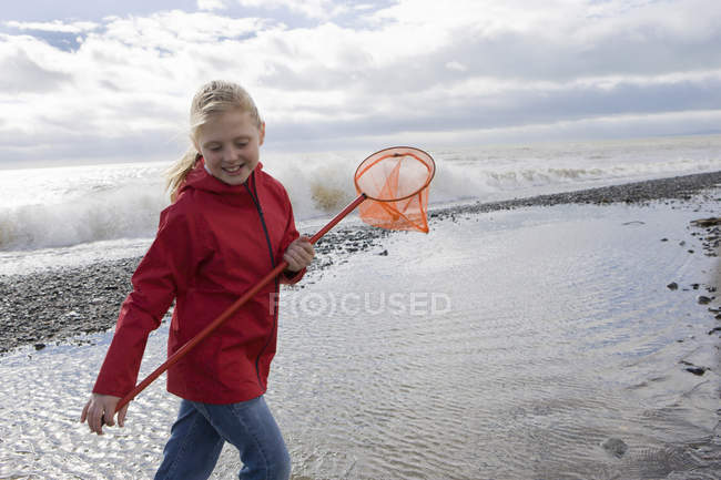 Young girl walking on beach with fishnet — Stock Photo