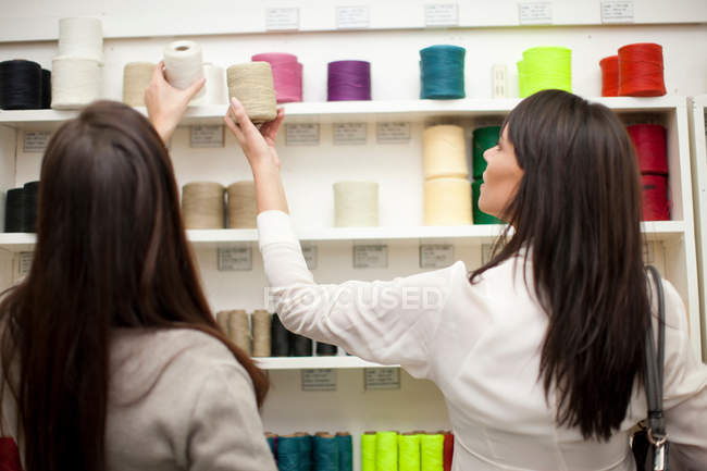 Mujeres eligiendo carrete de hilo en la tienda - foto de stock