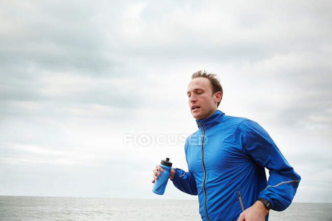 Чоловік біжить біля моря в похмурий день — стокове фото