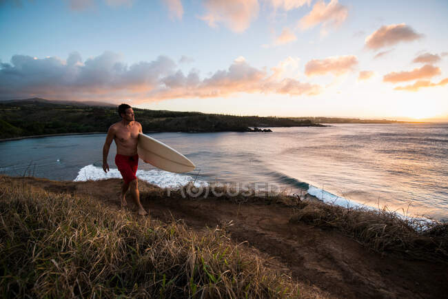 Surfista llevando tabla en la playa - foto de stock