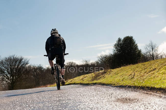 Человек на велосипеде по сельской дороге — стоковое фото