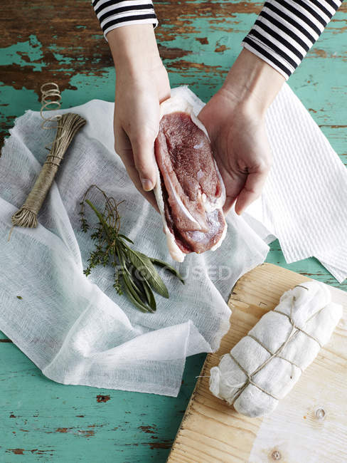 Mujer preparando prosciutto de pato paso 3, pecho de pato salado en muselina con ramillete garni - foto de stock
