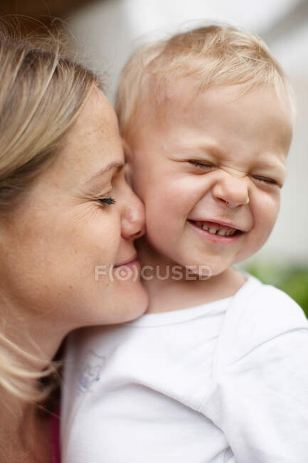 Mother kissing toddler boy outdoors — Stock Photo