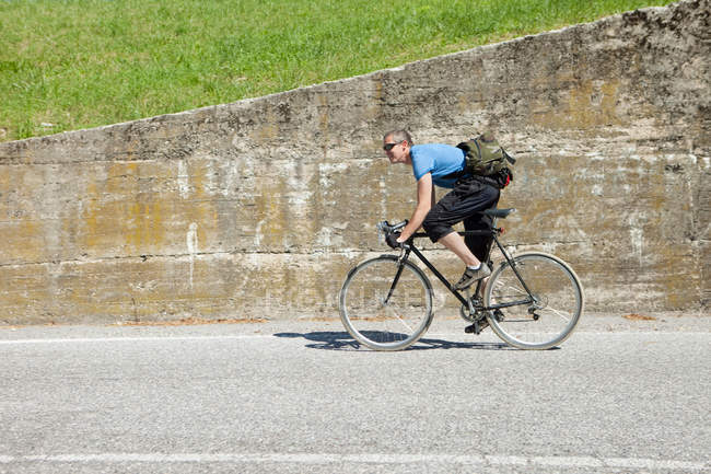 Vista lateral do ciclista pedalando subida — Fotografia de Stock