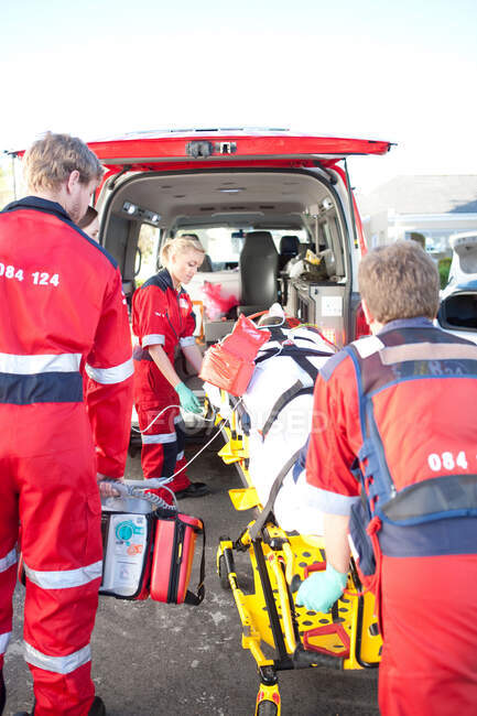 Paramédicos levantando mulher na maca em ambulância — Fotografia de Stock